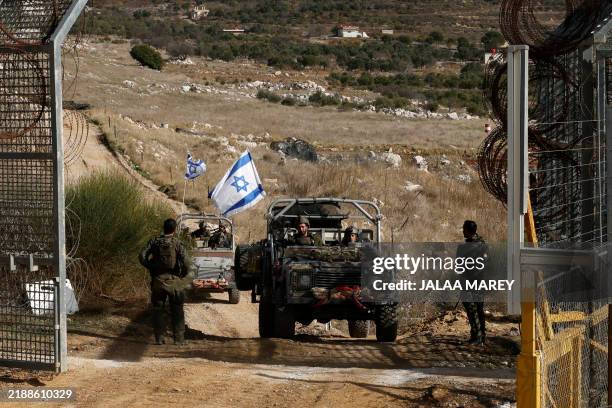 Israeli military vehicles cross the fence as they return from the buffer zone with Syria, near the Druze village of Majdal Shams in the...