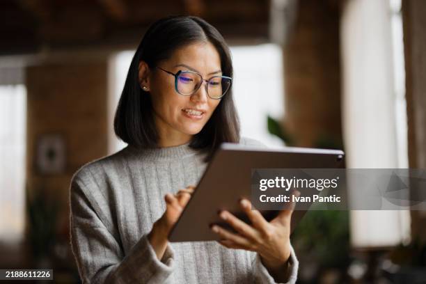 frau in eleganter freizeitkleidung, die auf tablet im modernen büro arbeitet - sich verschönern stock-fotos und bilder