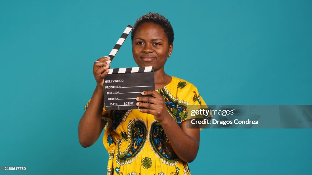 Female film producer using a clapperboard to say action in movie industry