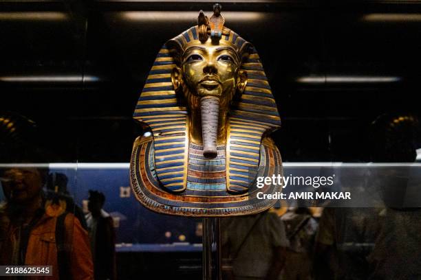 Visitors walk past the golden funerary mask of ancient Egyptian King Tutankhamun on display at the Egyptian Museum in Cairo on December 2, 2024.