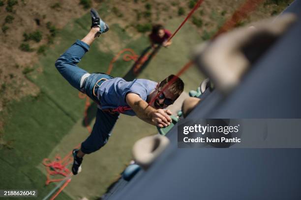 mann klettert outdoor felswand in active lifestyle abenteuer - seilabsperrung stock-fotos und bilder