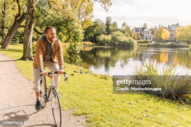 man riding bicycle along scenic lakeside path on a sunny day - fietspad stockfoto's en -beelden