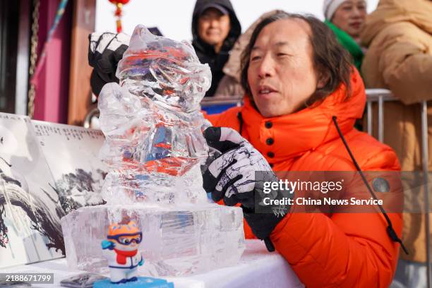 An inheritor works on an ice sculpture of the Asian Winter Games mascot Binbin during the opening ceremony for the 5th Harbin Ice Collecting Festival...
