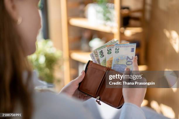 young woman takes out money euro banknotes from a leather wallet. - wallet stock pictures, royalty-free photos & images