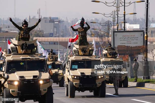 Members of Iraq's Popular Mobilization Forces ride a military vehicle during a military parade celebration of "Victory Day" marking the seventh...