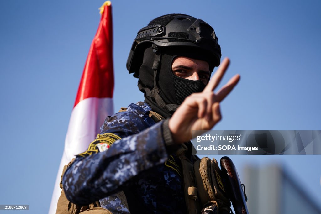 A member of the Iraqi police waving victory sign during a...