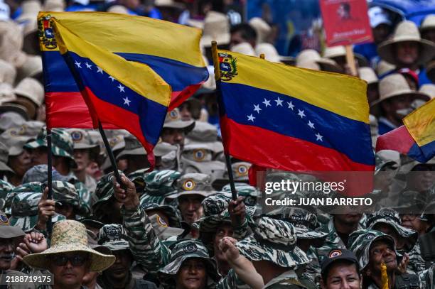 Members of the Bolivarian militia wave Venezuelan flags during an event marking the 165th anniversary of the Battle of Santa Ines in Caracas on...