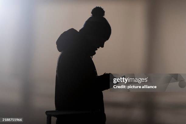 December 2024, Saxony, Altenberg: A man looks at a smartphone and is silhouetted. Photo: Sebastian Kahnert/dpa