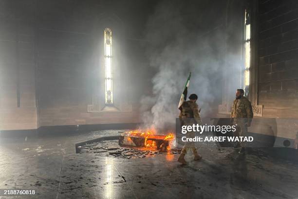 Rebel fighters stand next to the burning gravesite of Syria's late president Hafez al-Assad at his mausoleum in the family's ancestral village of...