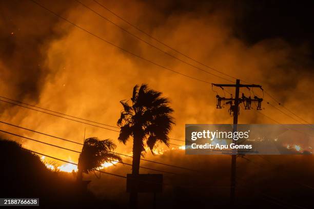 The Franklin Fire burns next to powerlines at he Pacific Coast Highway in the morning on December 11, 2024 near Malibu, California. The wildfire has...