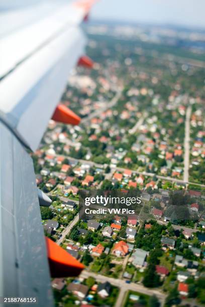 Overhead view of vibrant residential neighborhoods and surrounding greenery near Schönefeld Airport on a clear day.