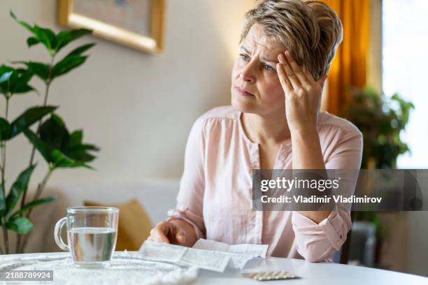 an anxious woman with her medication - hormone therapy stock pictures, royalty-free photos & images