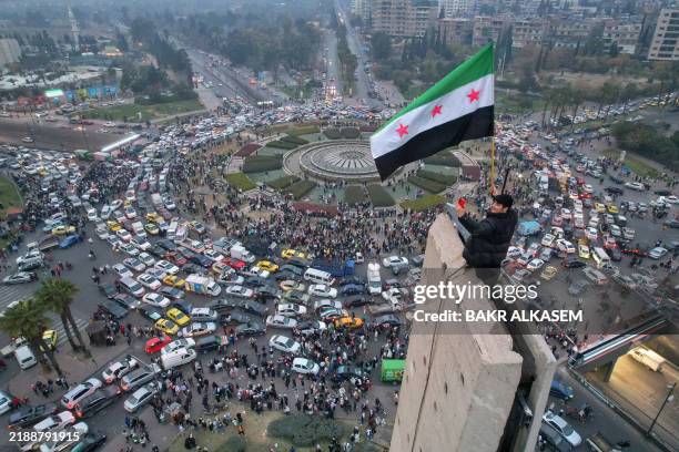 An aerial view shows a Syrian man waving the independence-era Syrian flag at Damascus' central Umayyad Square on December 11, 2024.