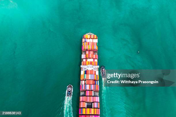 aerial view of cargo ship transporting containers across turquoise ocean - aguamarina fotografías e imágenes de stock
