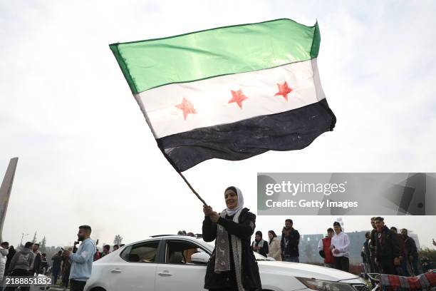 Woman waves the flag of the Syrian rebels as people gather to celebrate the fall of the government, in Umayyad Square on December 8, 2024 in...