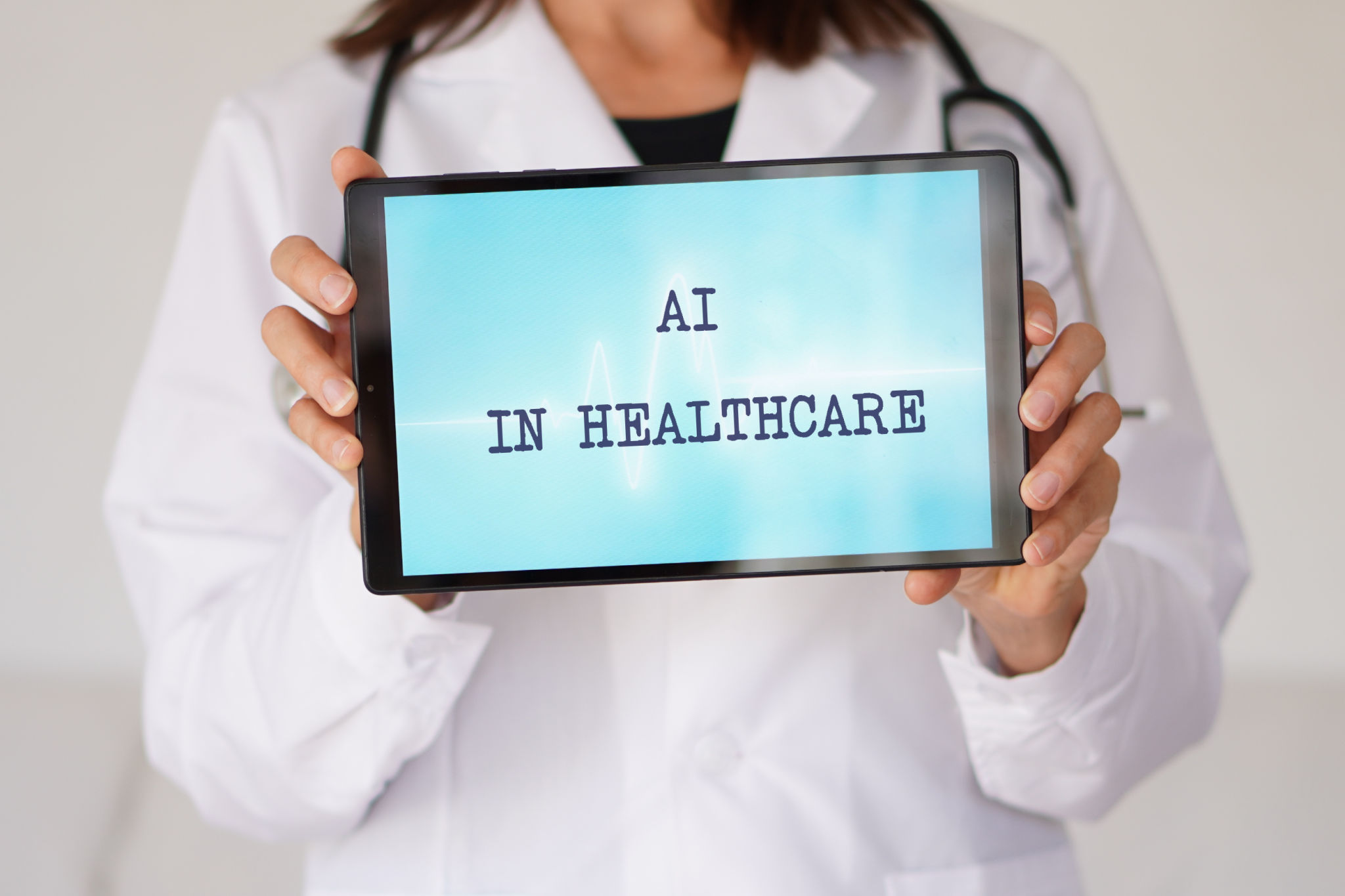ARTIFICIAL INTELLIGENCE IN HEALTHCARE concept. words written on a tablet held in the hands of a female physician. ARTIFICIAL INTELLIGENCE IN HEALTHCARE concept. words written on a tablet held in the hands of a female physician.