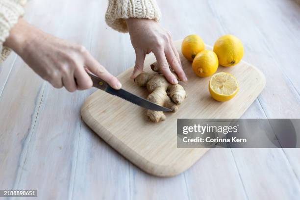 female hand cutting ginger on a wooden board with lemon - stock photo - limonade stockfoto's en -beelden