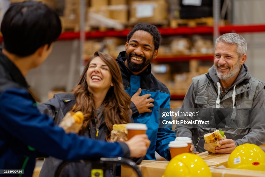 Trabalhadores multiculturais do armazém rindo e relaxando durante a pausa para o almoço