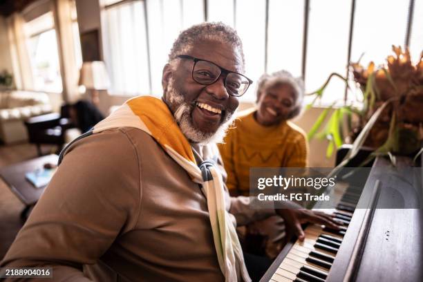 retrato de un hombre maduro tocando el piano con su esposa en casa - piano fotografías e imágenes de stock
