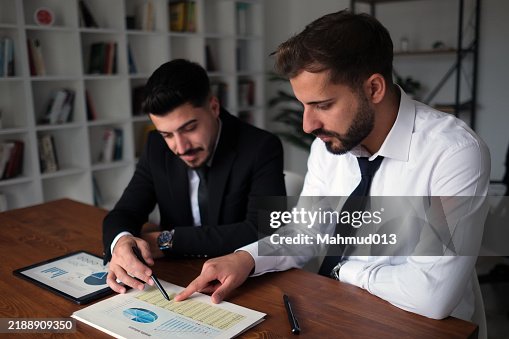 Colleagues analyzing data on documents and digital tablet at workplace Colleagues analyzing data on documents and digital tablet at workplace