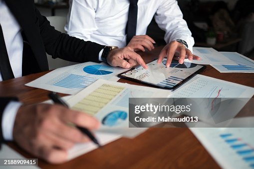 Colleagues analyzing data on documents and digital tablet at workplace Colleagues analyzing data on documents and digital tablet at workplace