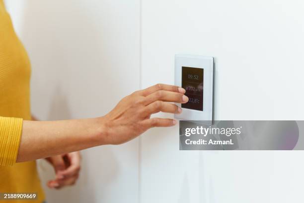 hispanische frau stellt thermostat im modernen zuhause ein - schalter stock-fotos und bilder