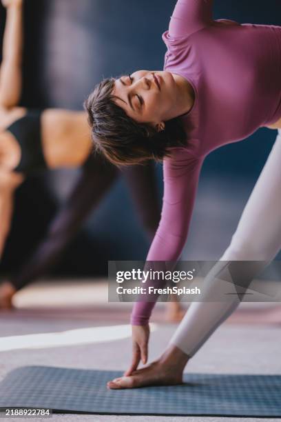 woman practicing yoga indoors embracing balance and tranquility in a studio - mat stock pictures, royalty-free photos & images