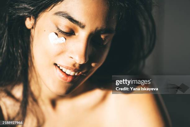 a beautiful asian woman enjoying a morning personalized skincare routine, applying a sunblocking moisturizer to her skin - collagen stock pictures, royalty-free photos & images