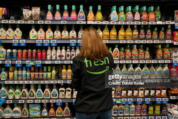 An employee arranges a salad dressing display at an Amazon Fresh grocery store on December 12, 2024 in Federal Way, Washington. Amazon recently held...