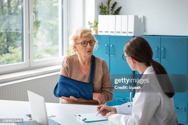 seniorin diskutiert mit ärztin - armbruch stock-fotos und bilder