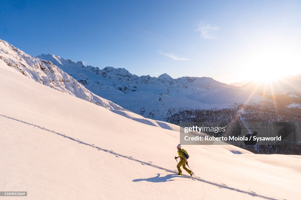 Ski mountaineer moving up on snowy mountain ridge