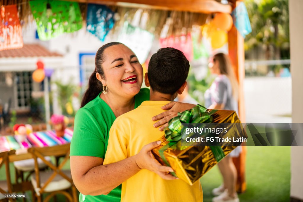Mature woman giving a gift to child nephew during birthday party at home