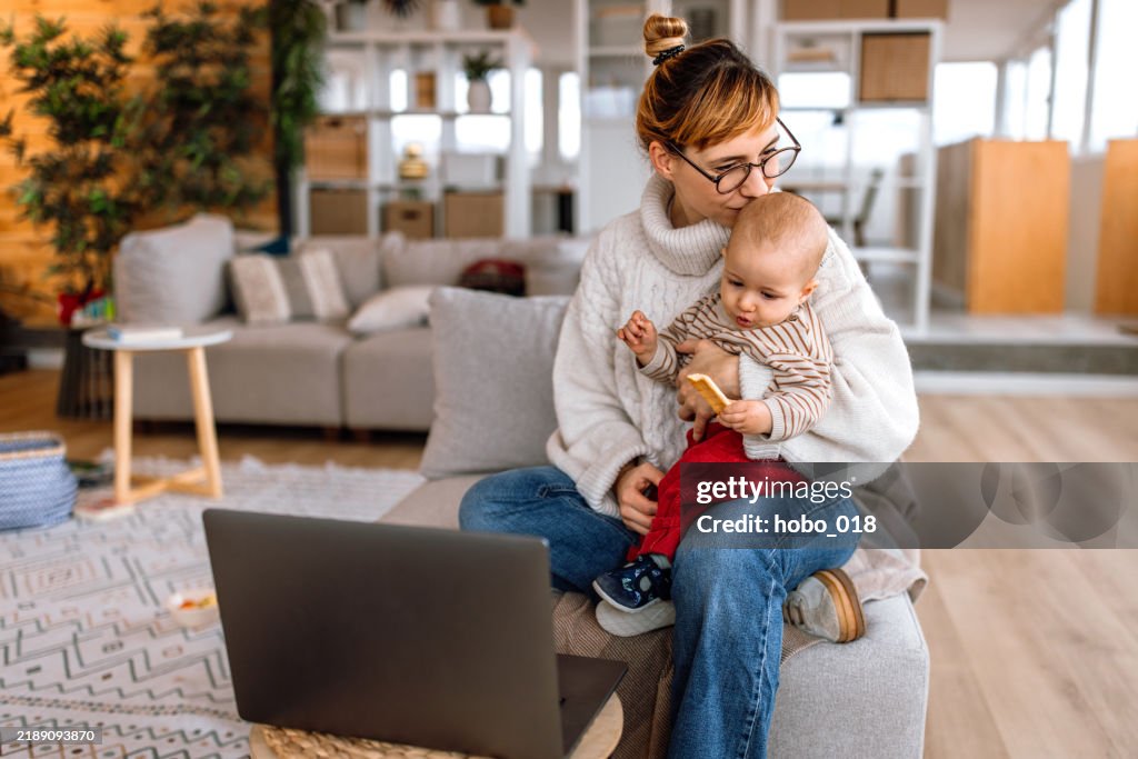 Berufstätige Mutter trägt einen kleinen Jungen während eines Videoanrufs