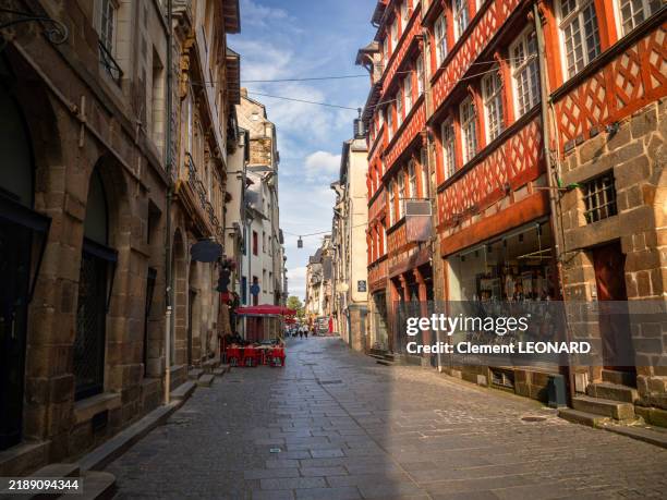 wide angle view of a cobblestone shopping street in the historic district of rennes, lined with traditional breton half-timbered buildings housing shops, restaurants and cafes, ille-et-vilaine - bretagne (brittany) - western france. - rennes france stock pictures, royalty-free photos & images