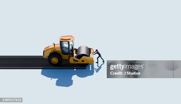 compactor paving a road with a man pushing against it - struggle against progress concept - pressmaschine stock-fotos und bilder