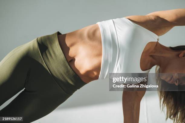young slim woman in sportswear in modern studio. fitness girl with beautiful abdominal muscles - tour de taille photos et images de collection
