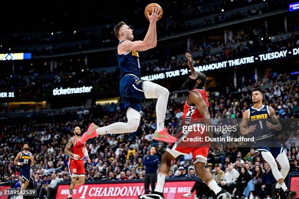 Christian Braun of the Denver Nuggets scores on a layup under coverage by James Harden of the LA Clippers in the first half at Ball Arena on December...