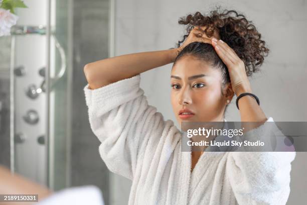 young woman tying her hair in the bathroom after shower - hair back stock pictures, royalty-free photos & images