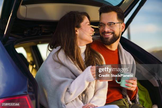 coppia con tazza di caffè o tè seduta nel bagagliaio dell'auto - bevanda calda foto e immagini stock