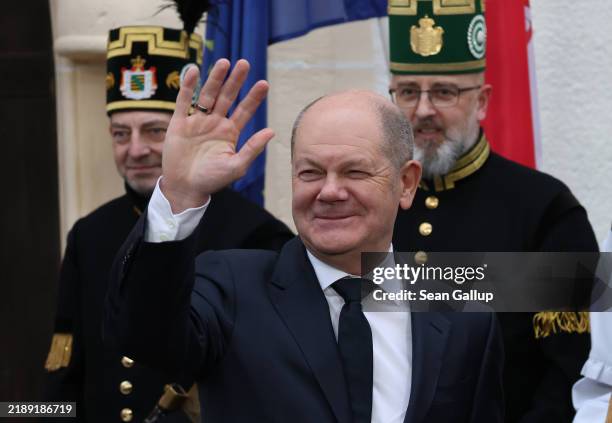 German Chancellor Olaf Scholz waves as men dressed in the ceremonial uniforms of Saxon miners look on before Scholz met with Serbian President...