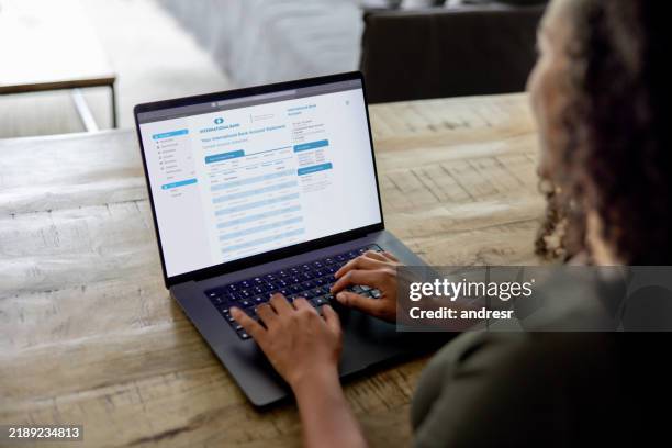 mujer en casa revisando su extracto bancario usando una computadora portátil - banca electrónica fotografías e imágenes de stock