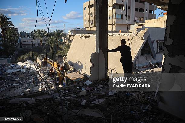 Man watches as rescuers search the rubble for casualties following an Israeli strike on the municipality building in Deir el-Balah in the central...