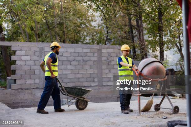 bauarbeiter bedienen zementmischer auf der baustelle - betonmischmaschine stock-fotos und bilder