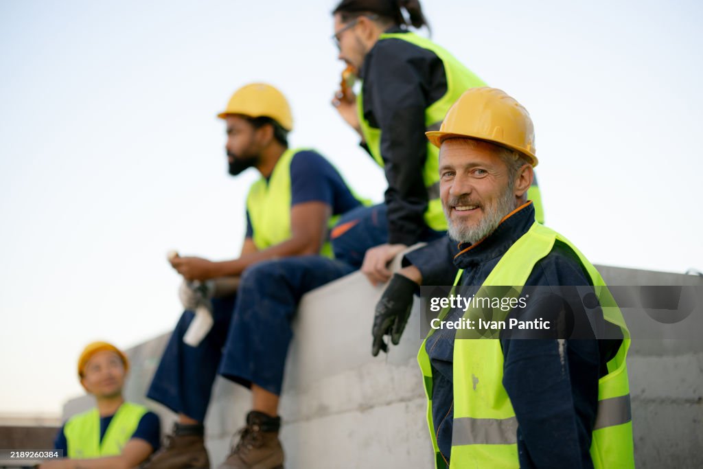 Smiling Construction Workers In Safety Gear Taking A Break On Site