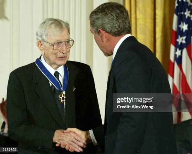 President George W. Bush shakes hands with former basketball coach John R. Wooden after presenting Wooden with a Presidential Medal of Freedom during...