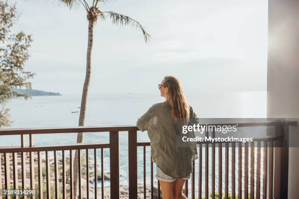 woman relaxing on balcony overlooking ocean at sunset - phuket province stock pictures, royalty-free photos & images