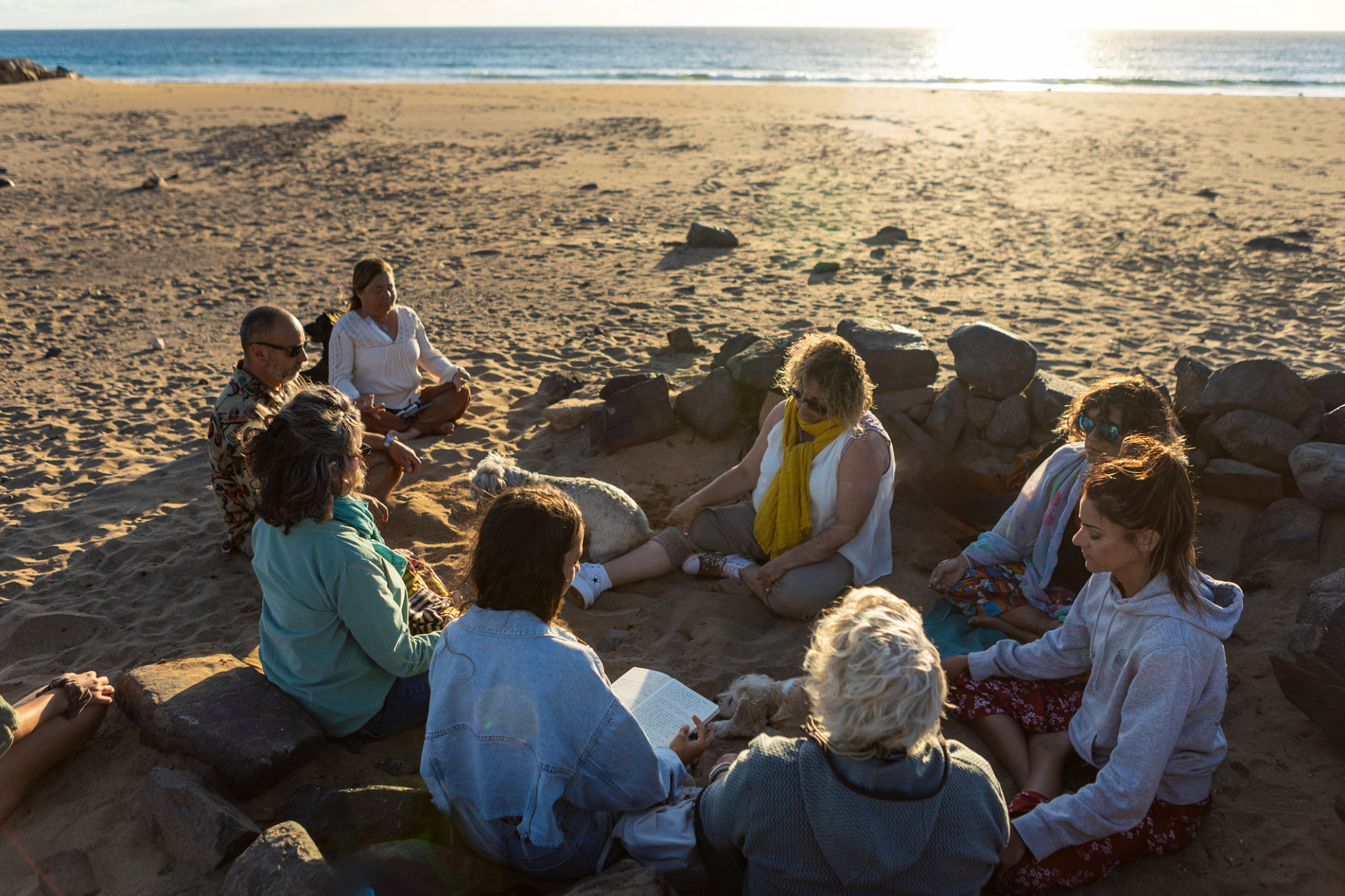 Group of people meditating together at sunset on the beach during spiritual retreat Group of people meditating together at sunset on the beach during spiritual retreat