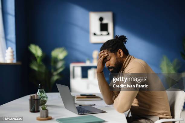 black male entrepreneur holding his head in pain at the office. - pressão física imagens e fotografias de stock