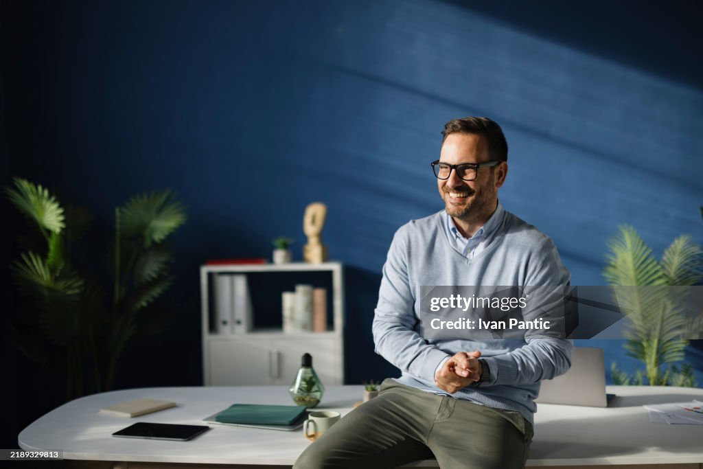 Happy businessman relaxing on a desk in the office.