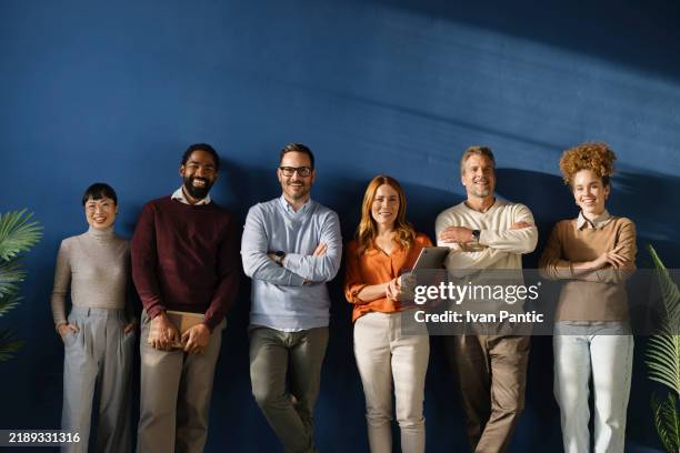 team of happy entrepreneurs standing against the wall in the office. - menschenreihe stock-fotos und bilder
